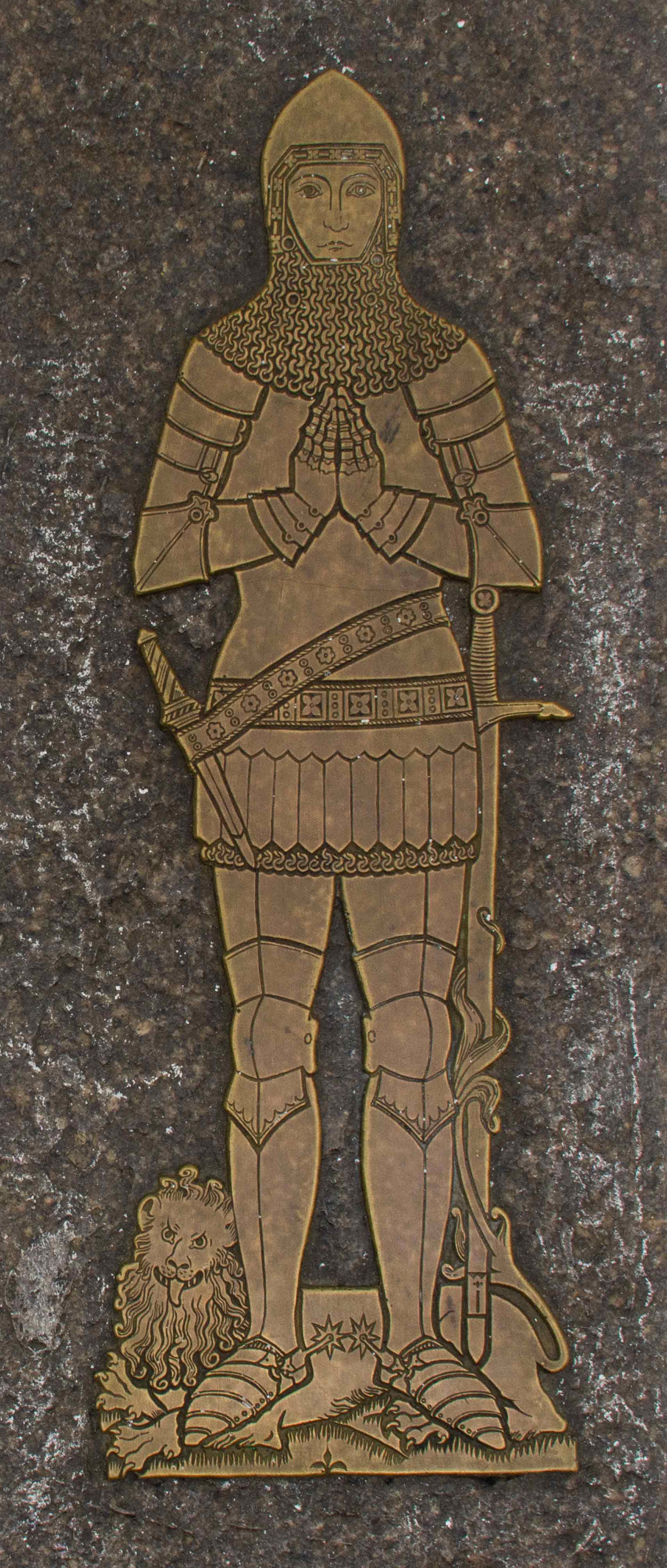 detailed image of a knight in armor with hands in a prayer position engraved onto brass