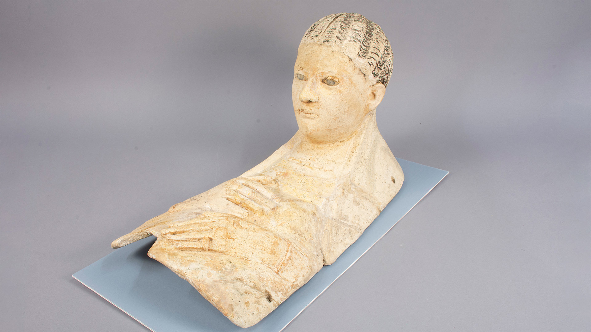 terracotta burial portrait of a woman's upper body including her face, jewelry, and hands