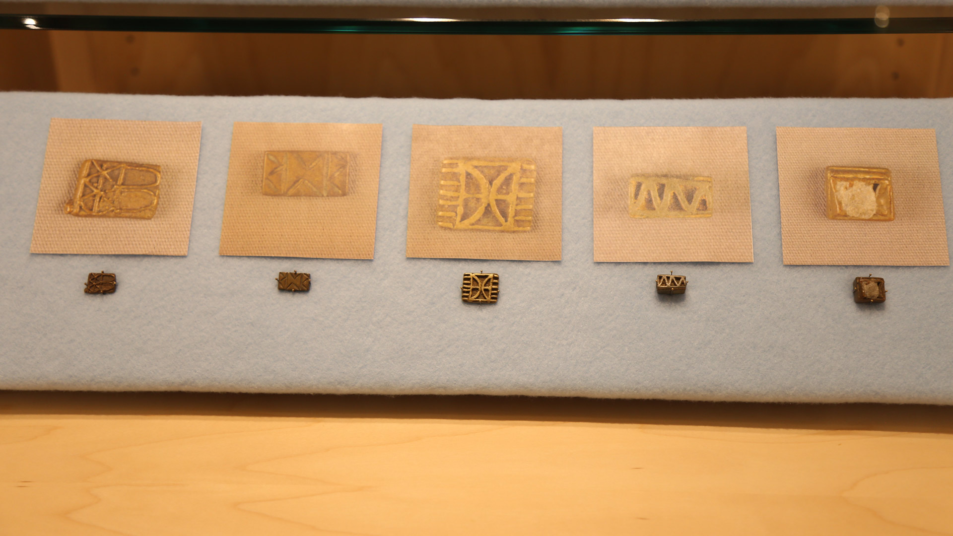 left case bottom shelf with five small gold weights