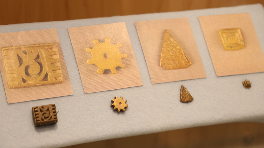 left case top shelf with four small gold weights