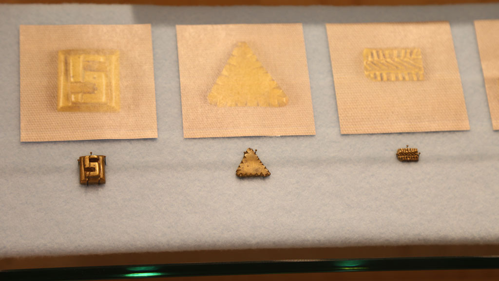 left case left half of middle shelf with three small gold weights