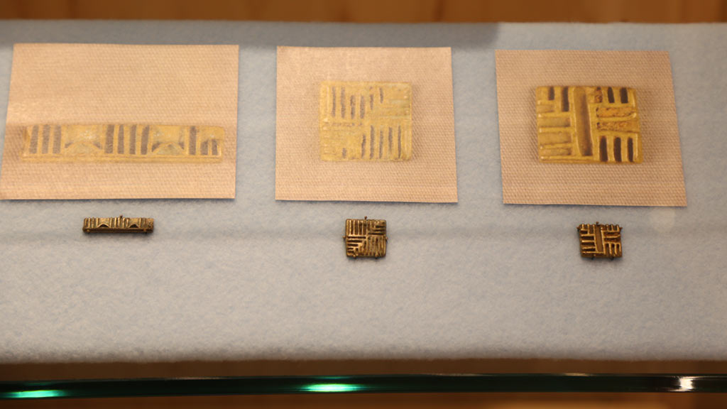 left case right half of middle shelf with three small gold weights