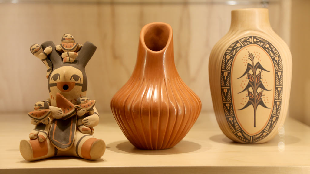 a wide shot of the bottom shelf in the left case showing off more pottery and a figure