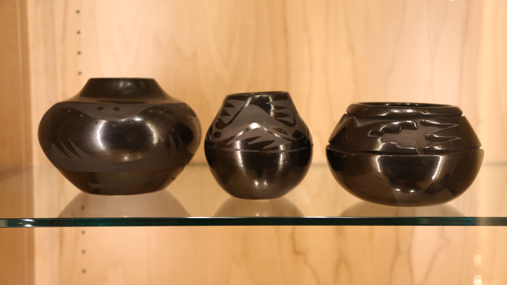 a wide shot of the middle shelf in the left case showing black pottery