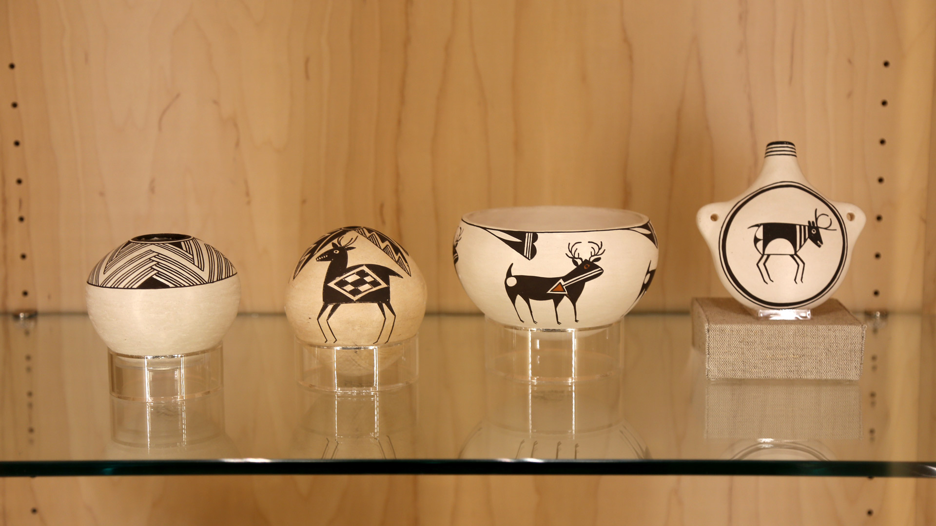 a wide shot of the top shelf in the left case showcasing pottery with designs and animals on them