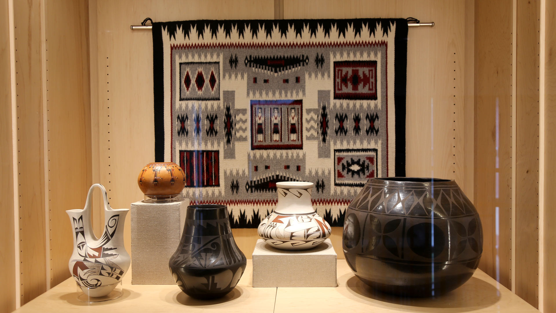 wide shot of the right case with the pottery and rug