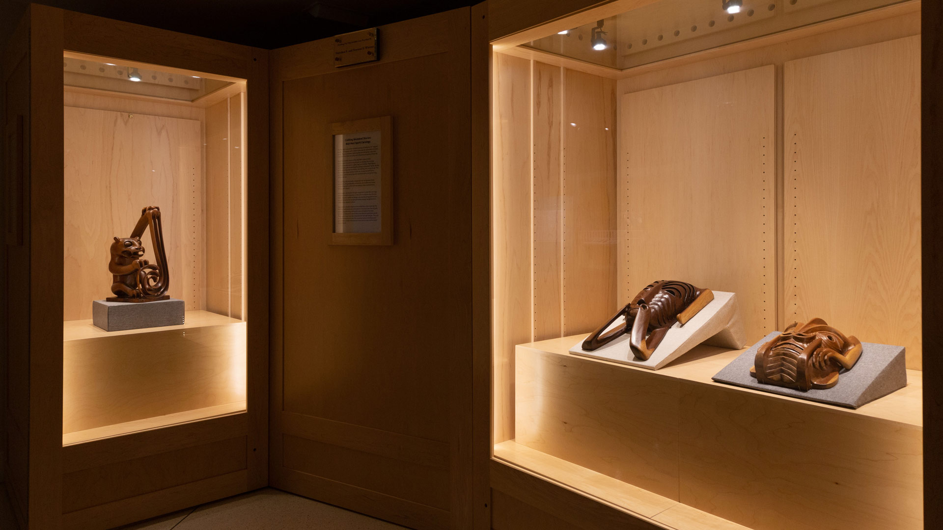 Three Mah Meri woodcarvings in a display case