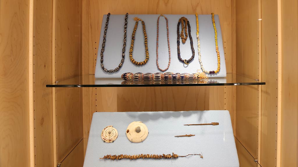 strings of beads, shells, objects that look like needles sitting on two shelves