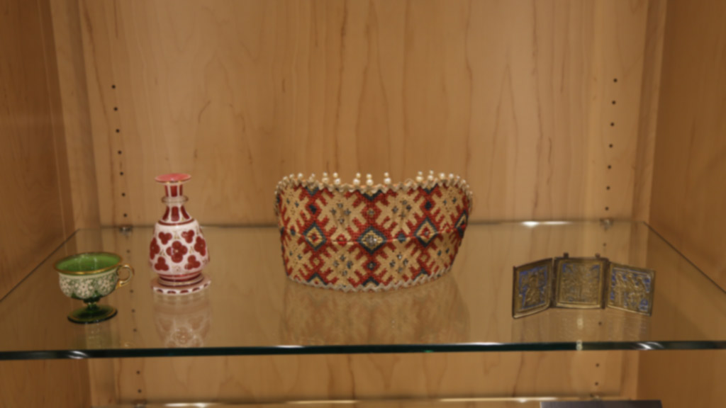 focused shot of the green cup, red bottle, and woven band of sorts alongside a metal decoration that opens up