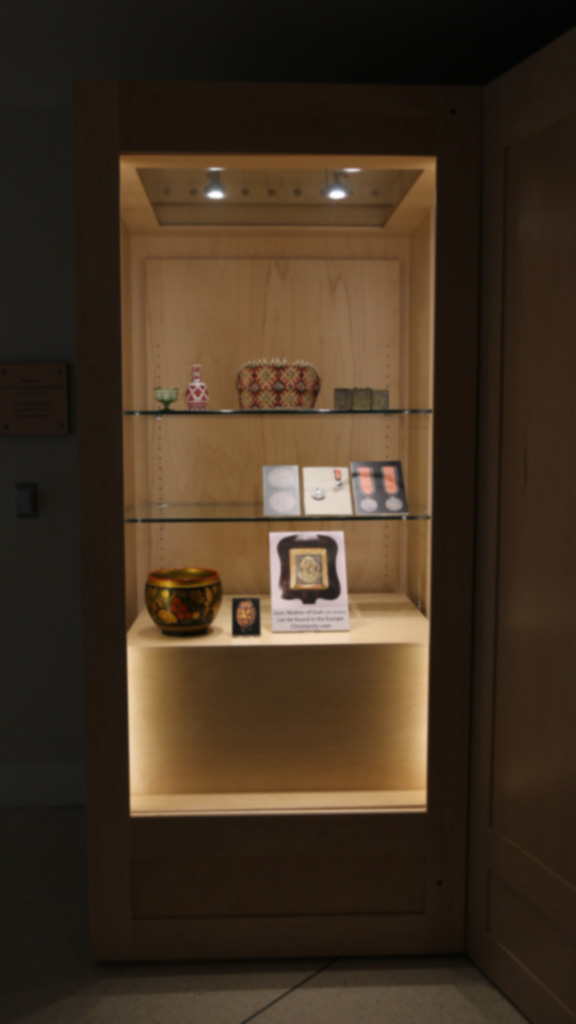 a shot of the left case and all it contains, which is the cup, bottle, band, metal object, silver medals, vases and 'mother of god' icon