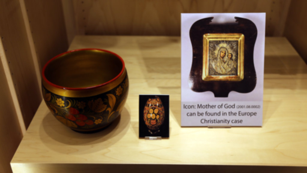 a decorative vase-like containter next to a picture of what appears to be a decorative vase. They are next to a 'mother of god' icon that depicts mary and jesus