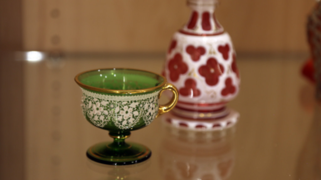 close-up of what appears to be a green and gold cup as well as a red and white bottle, both have floral patterns