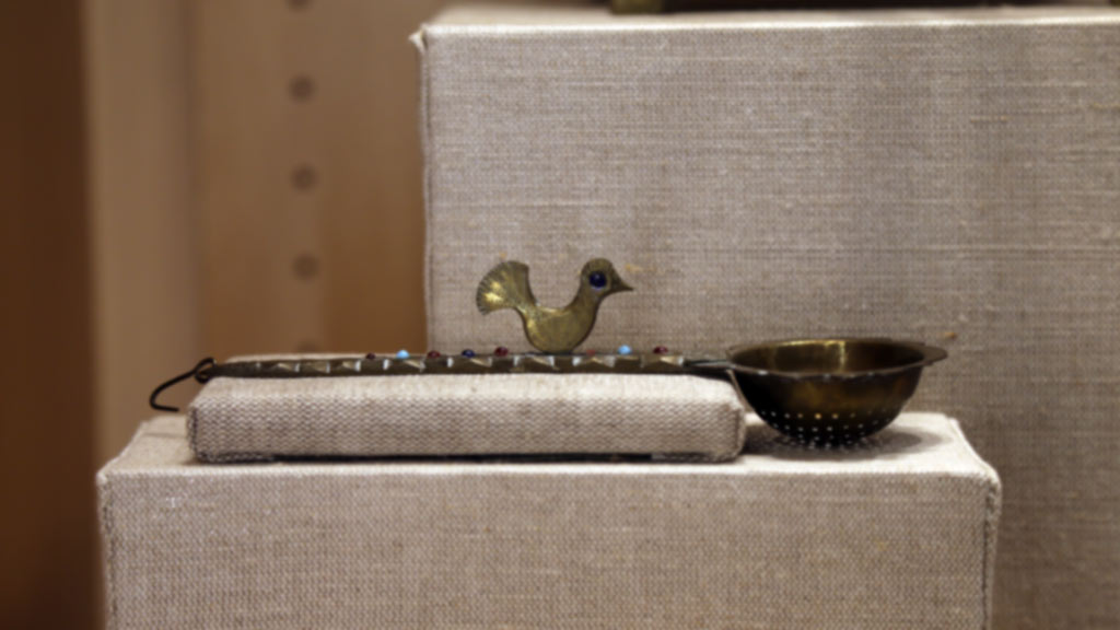a metal spoon-like apparatus decorated with some circular colors on top and a bird decoration
