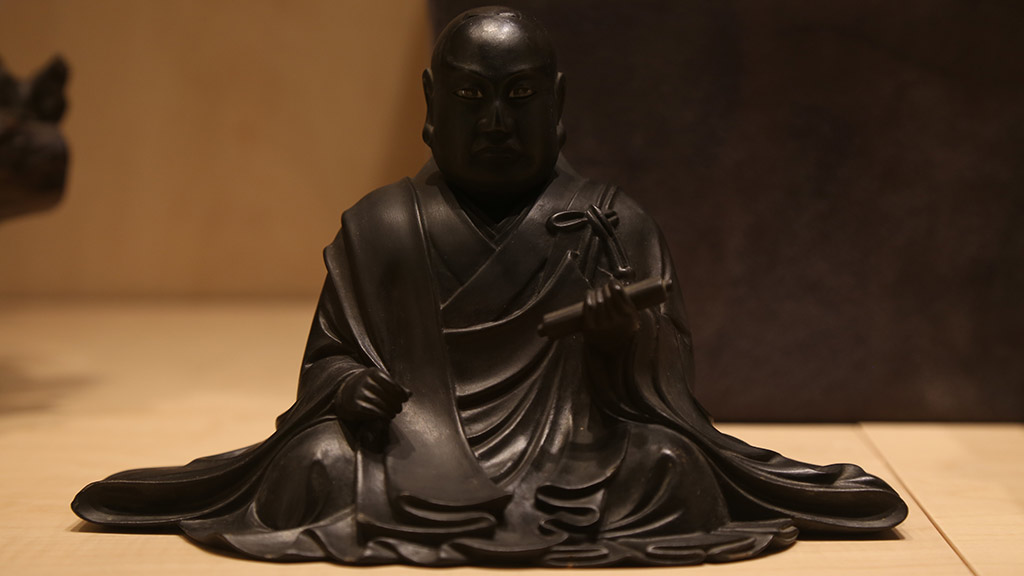 close-up of a man in a robe sitting and holding a scroll