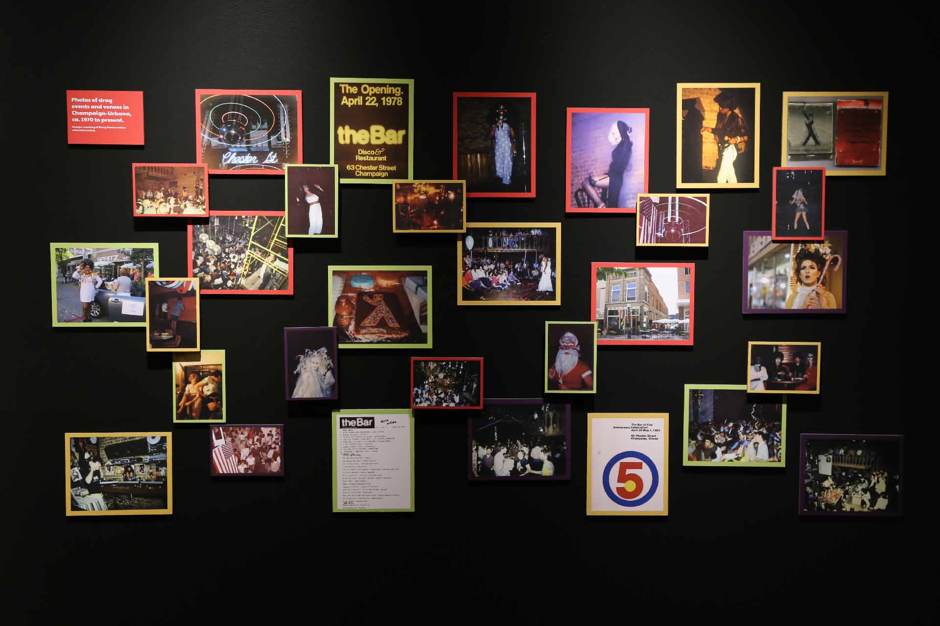 black wall with many photographs of drag events and other relevant imagery