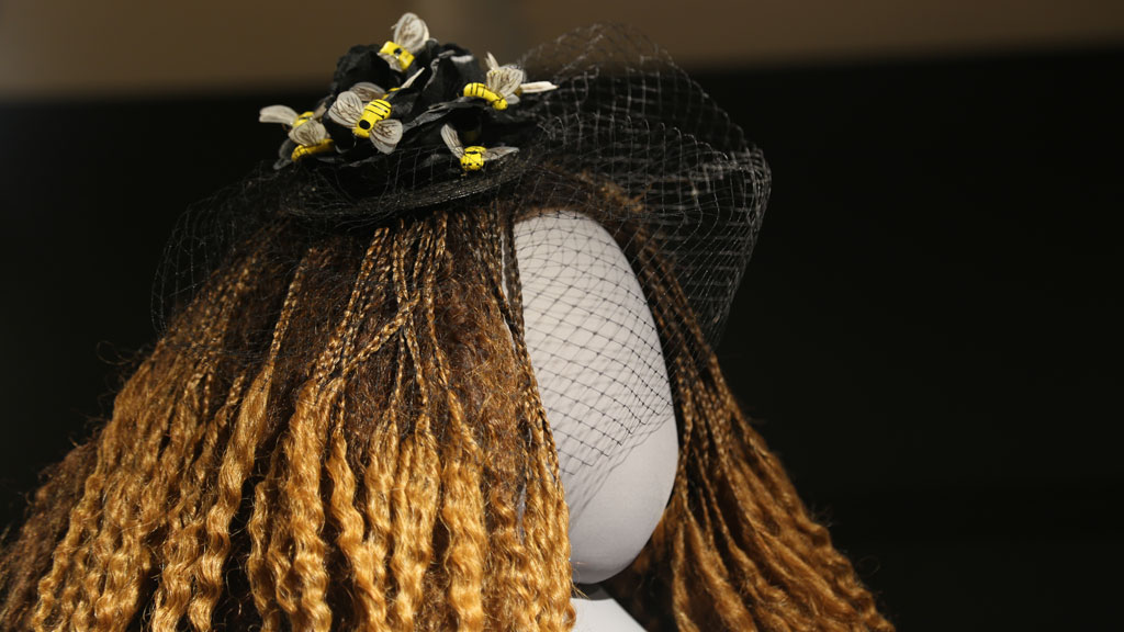 closeup of head of mannequin with a hat with a veil and bees attached