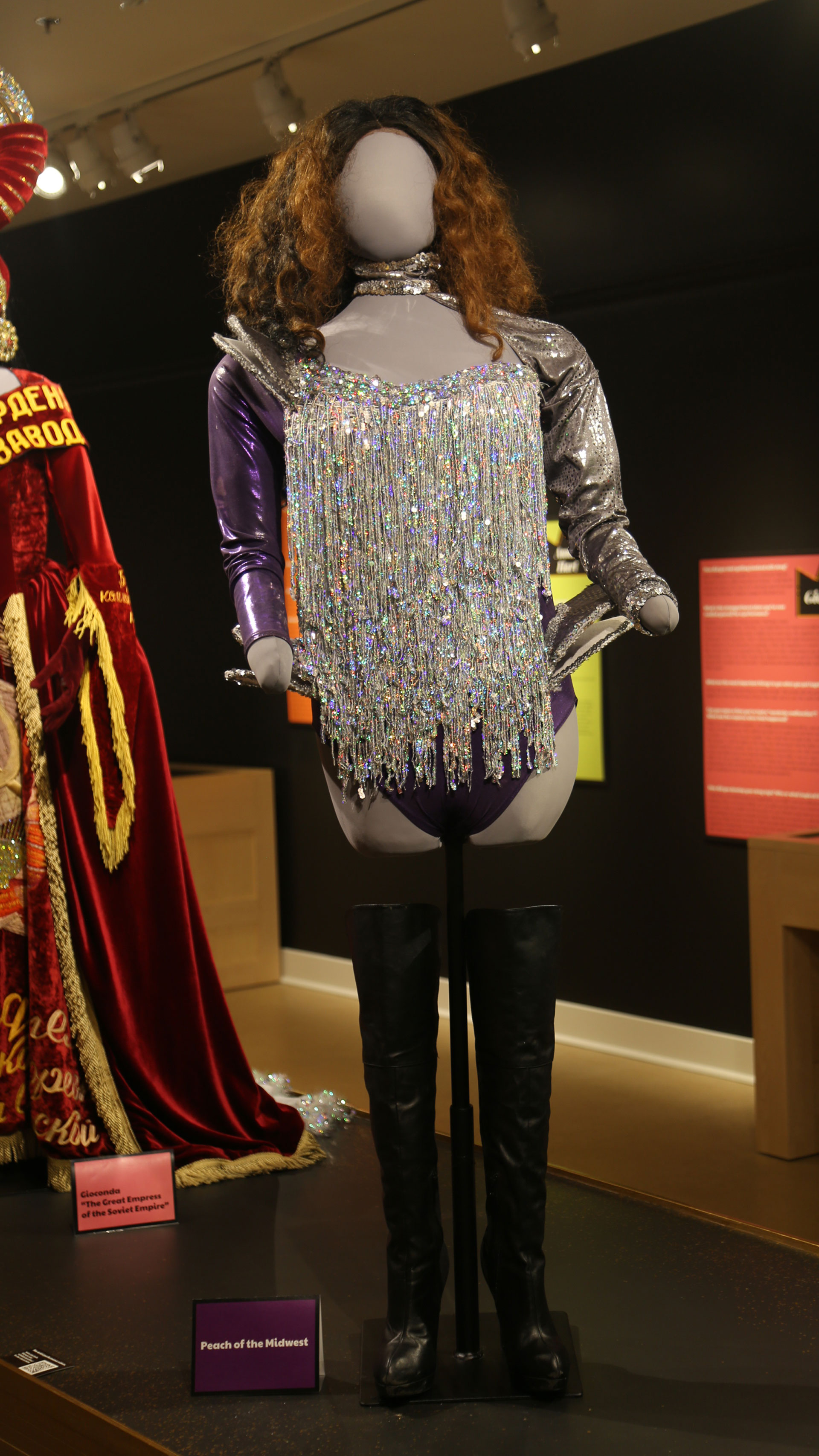 full view of mannequin with a sparkly costume with one purple sleeve with black boots