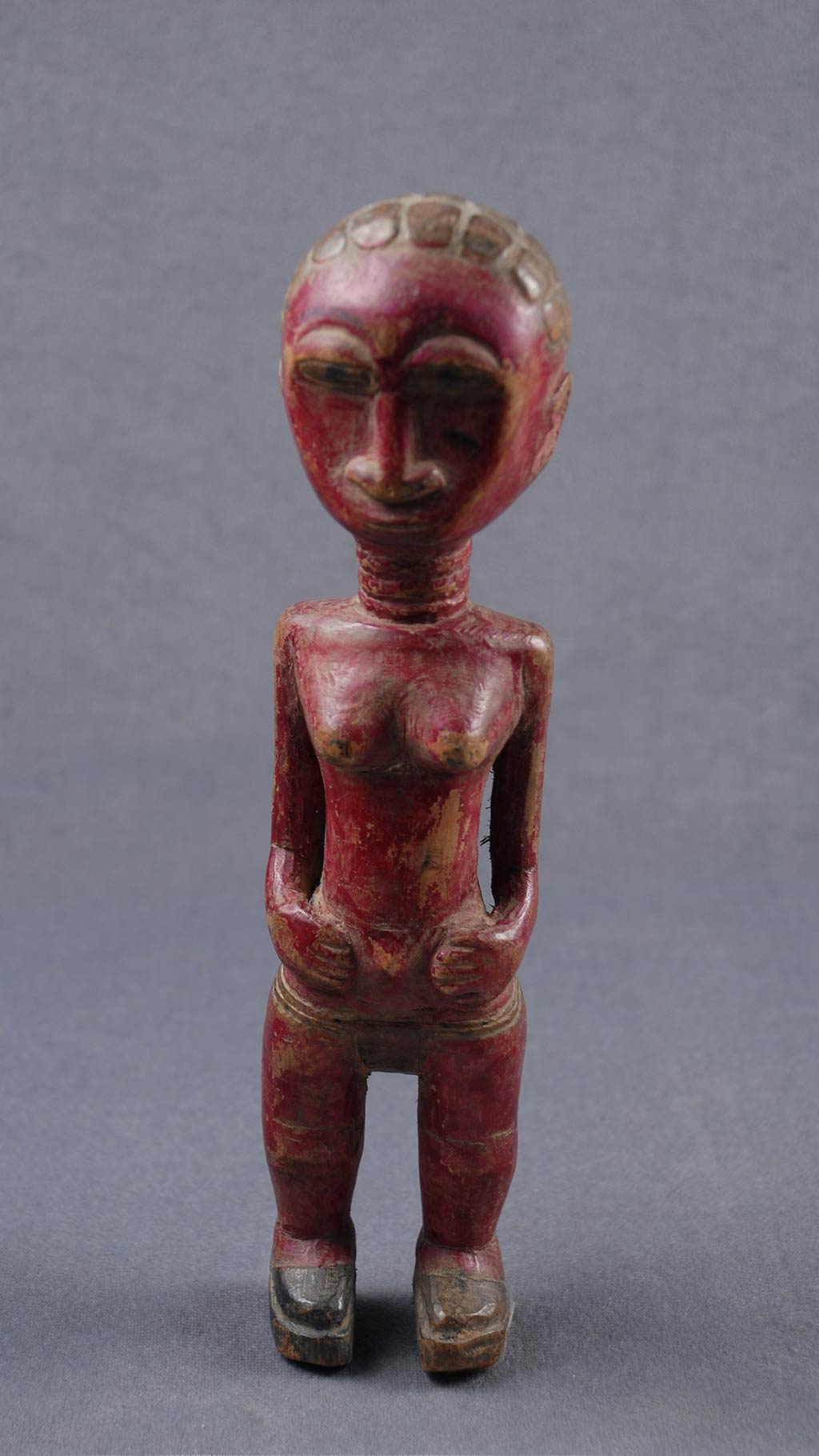 Dark red and brown wooden figure of a female with short brown hair.