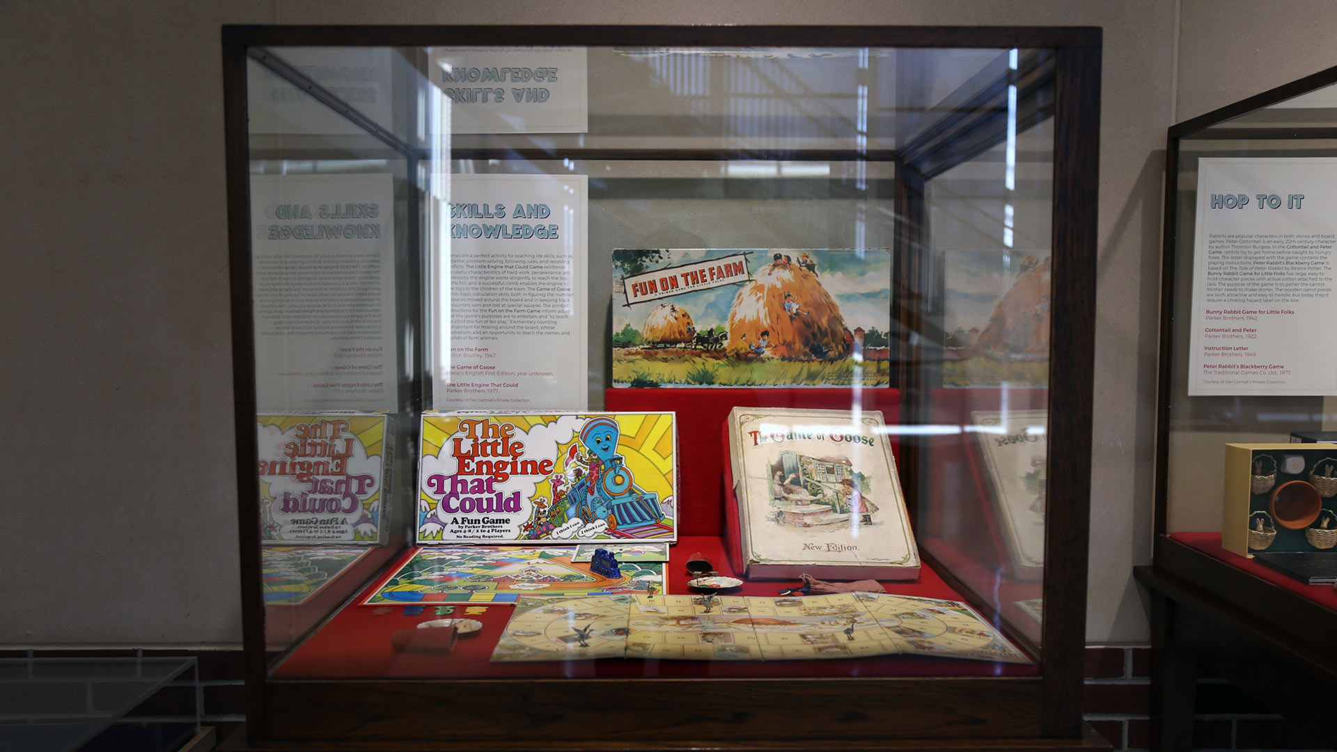 display case with the games 'the little engine that could', 'fun on the farm', and 'the game of goose'